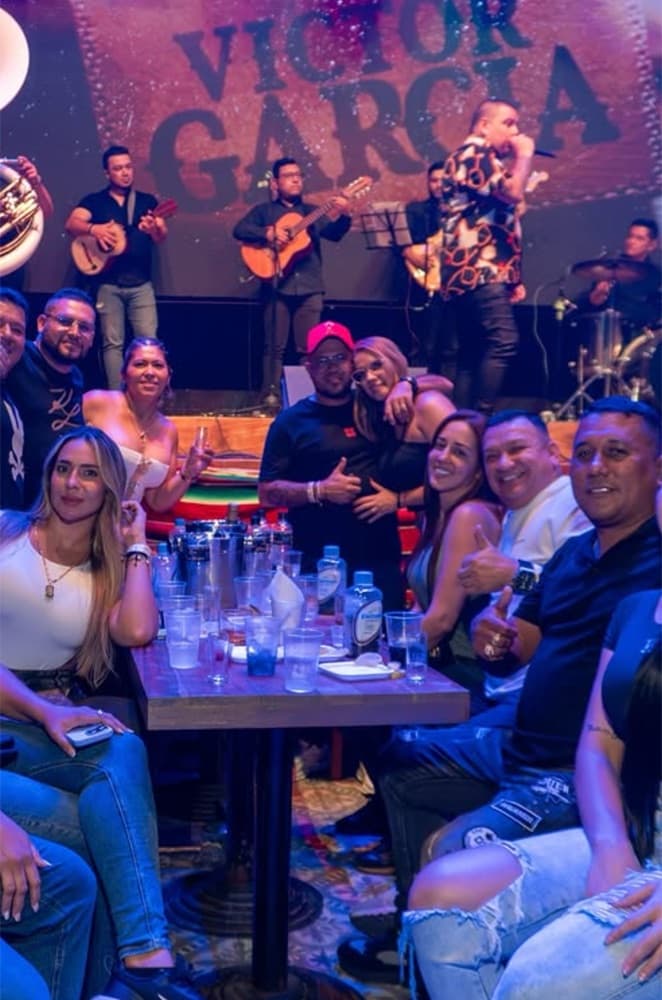 Grupo de amigos brindando en su mesa frente a la tarima de Plaza Juárez